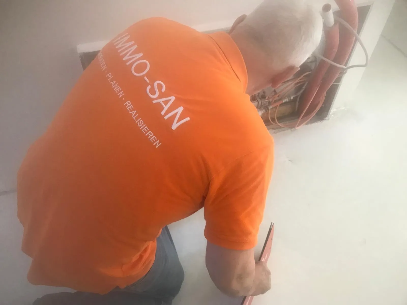 Rolf Lösch prüft auf der Baustelle einen Heizkreisverteiler in der Wand