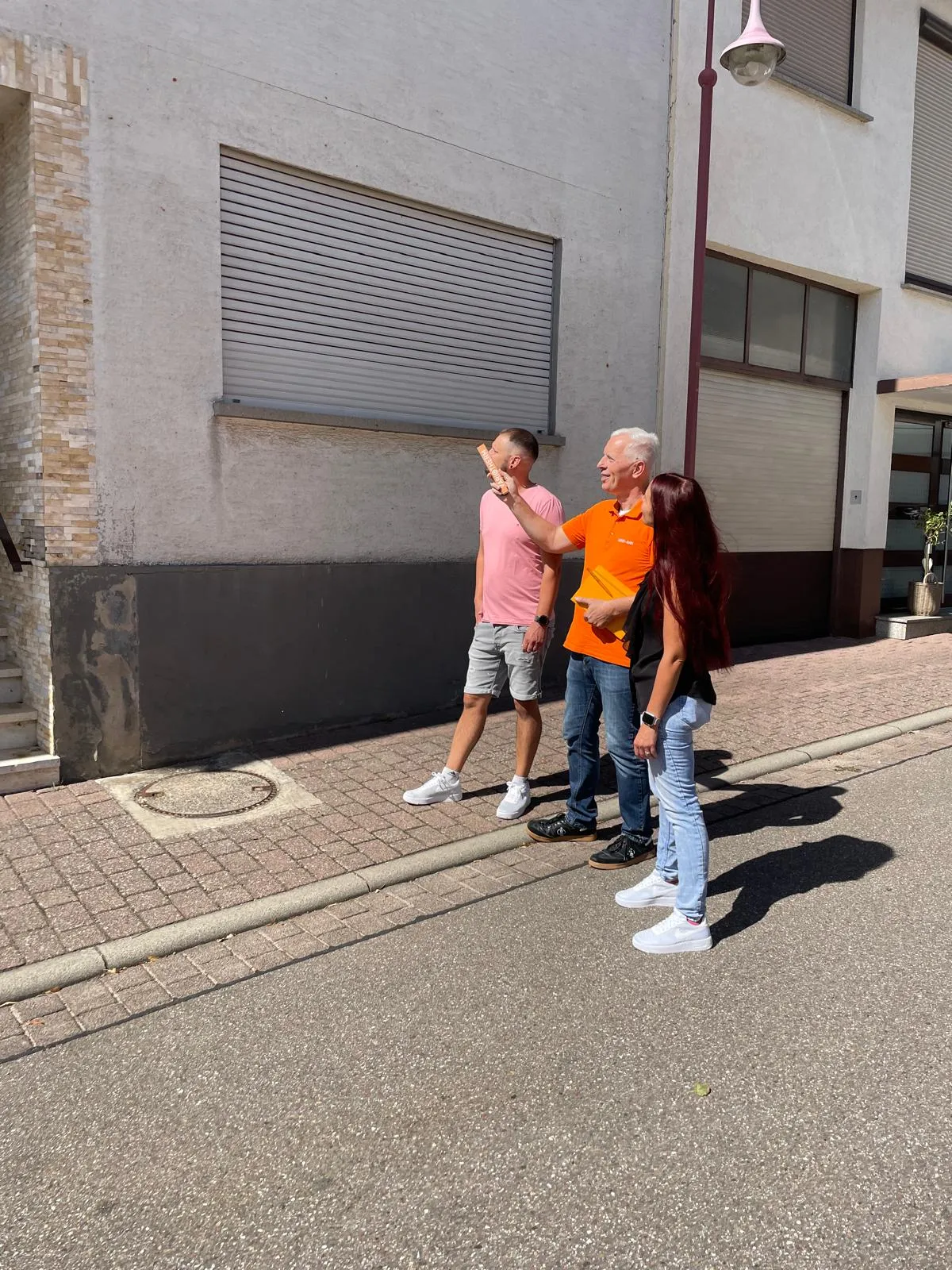 Eine Familie steht mit Rolf Lösch vor der Fassade ihrer Immobilie