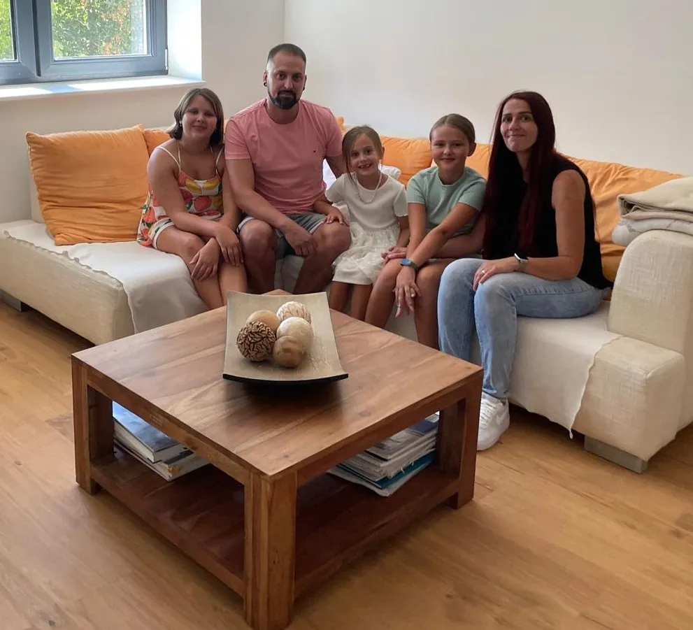 Eine Familie sitzt zusammen auf dem Sofa im fertig sanierten Haus