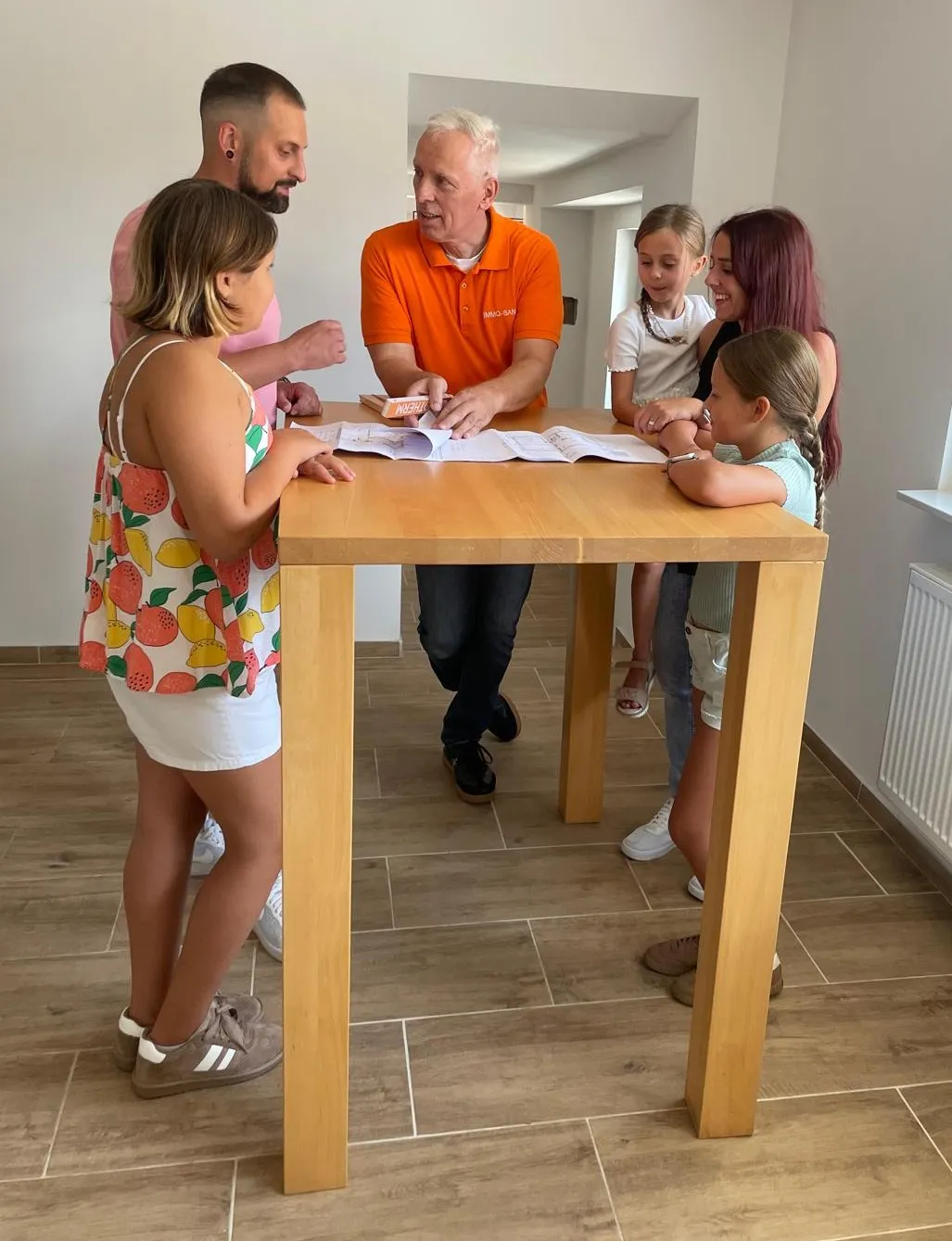 Rolf Lösch erklärt einer Familie den Grundriss am Tisch
