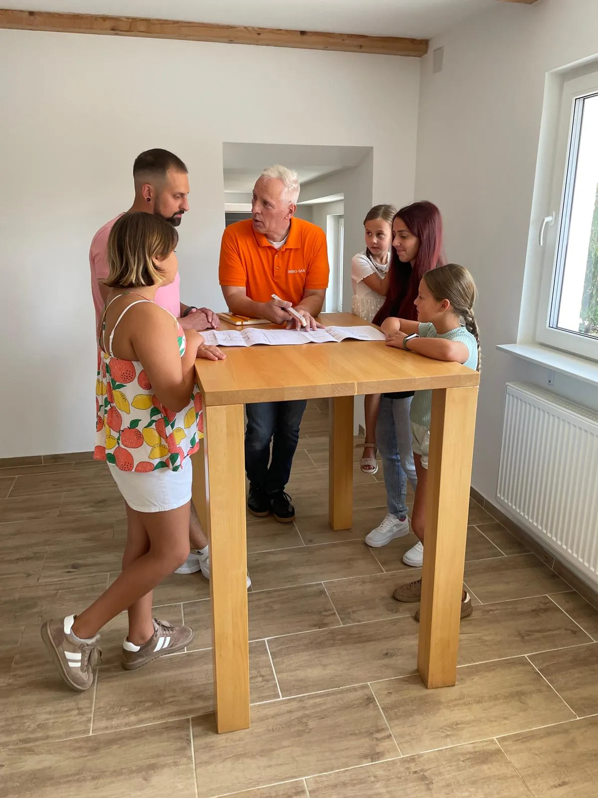 Eine Familie steht mit Rolf Lösch am Stehtisch über dem Grundriss