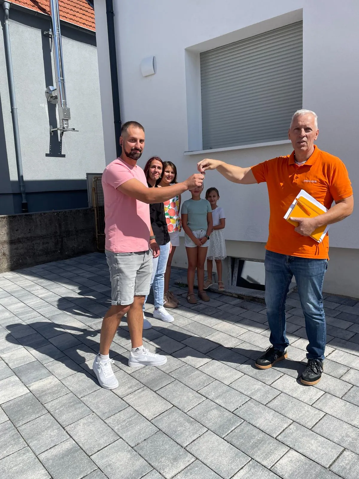 Schlüsselübergabe an die Familie vor dem fertig sanierten Haus